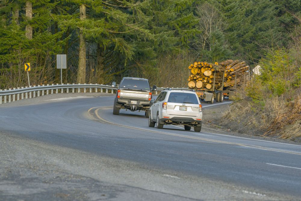 Photo of OR 6 showing a log truck going around a curve and two other vehicles